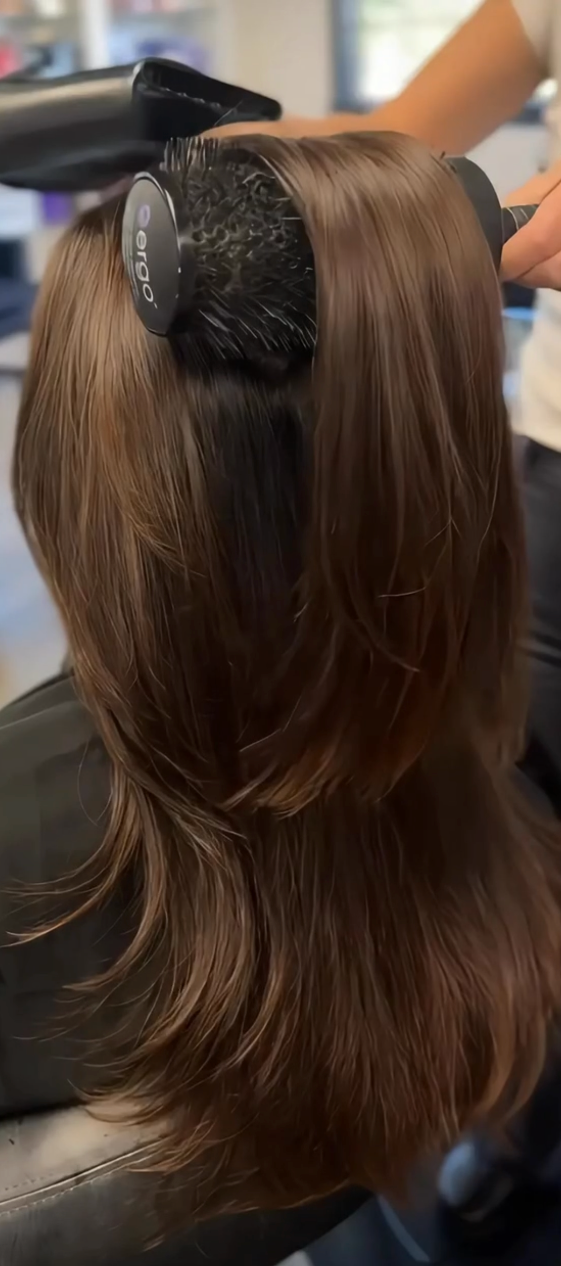 Stylist blow-drying brunette hair at Paradigm Salon